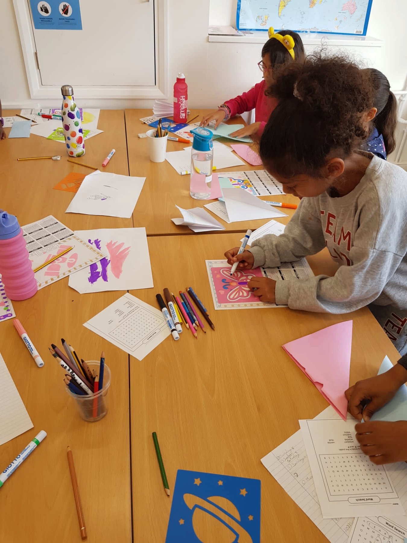 A table of children drawing, colouring and doing puzzles together
