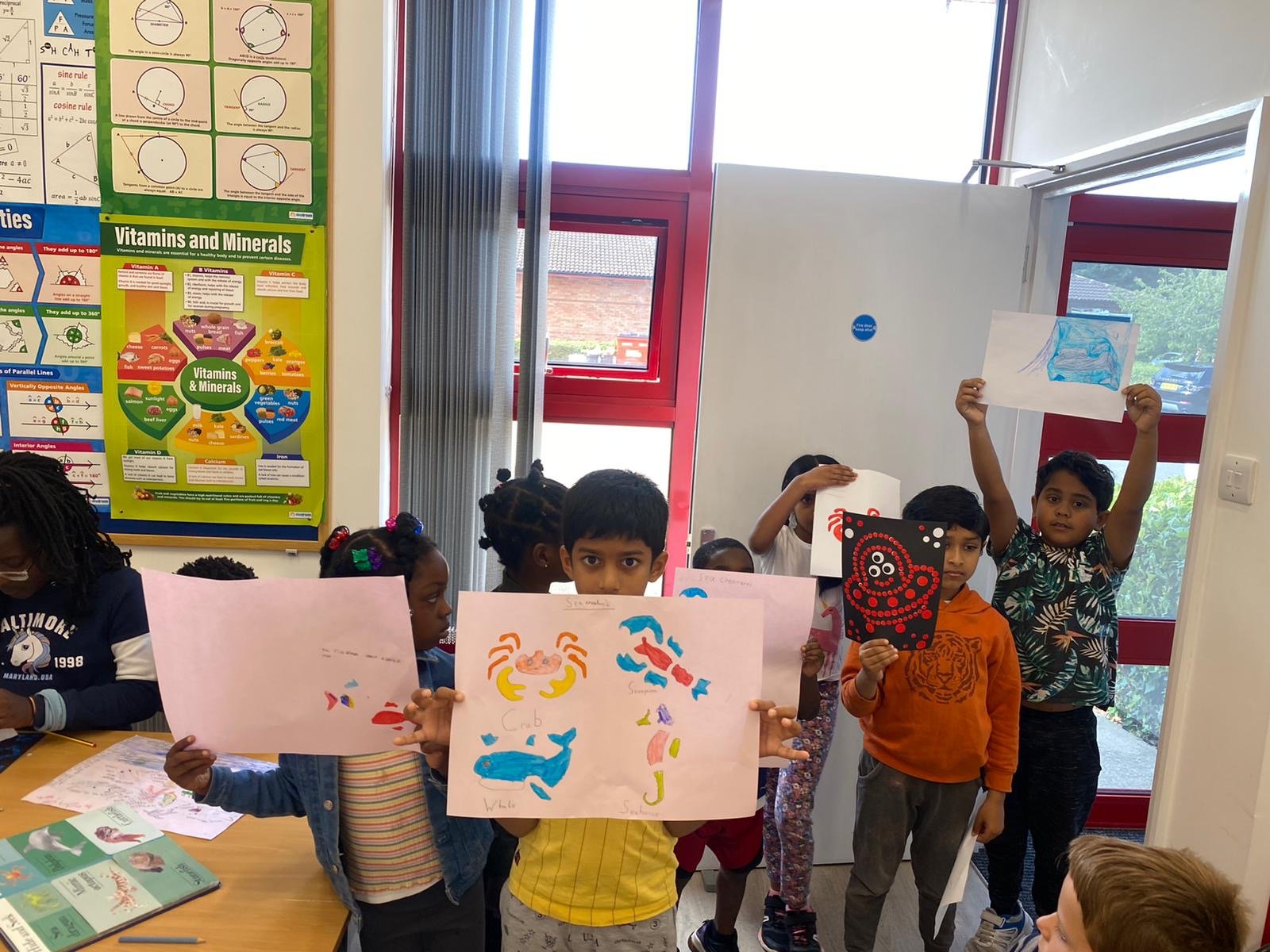 Children holding up bright, hand-painted sea-creatures artwork