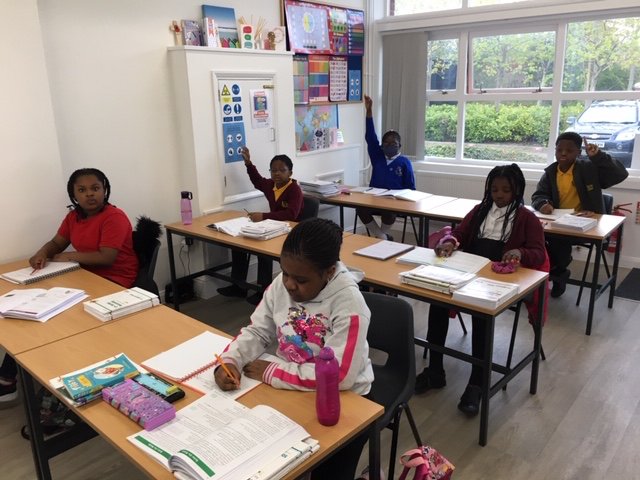 A primary tuition class raising hands in a bright room at Firm Foundation Centre